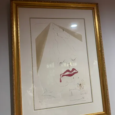 Framed Salvador Dalí surrealist print featuring a face motif, presented in an ornate gilded frame with a double mat.