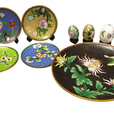 Sale Photo Thumbnail #292: Collection of Chinese cloisonné decorative items including floral pattern plates, saucers, and three small eggs on stands.