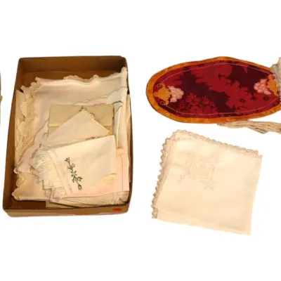 Sale Photo Thumbnail #210: Assortment of vintage linens, including embroidered and lace-edged napkins, doilies, and a red patterned oval mat.