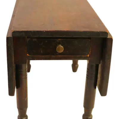 Sale Photo Thumbnail #110: Vintage dark stain wooden drop-leaf side table featuring a single drawer with a brass knob and turned legs, showing light surface wear.