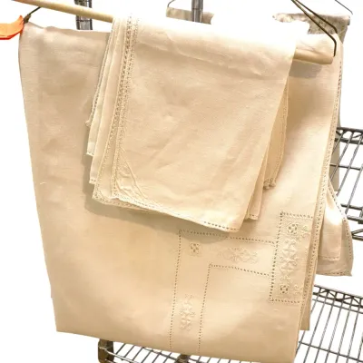 Sale Photo Thumbnail #207: Vintage off-white embroidered linen tablecloth set with matching napkins hanging on a wooden rod hanger.