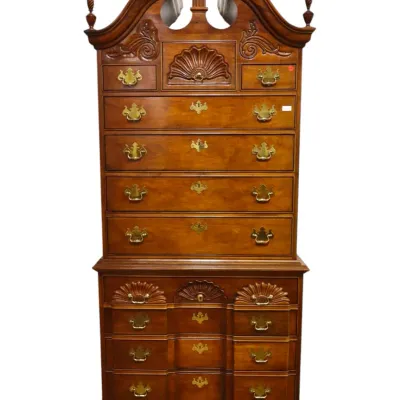 Sale Photo Thumbnail #230: Queen Anne-style highboy chest on chest featuring a bonnet top with carved finials, carved shell motifs, and brass batwing hardware.