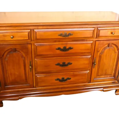 Sale Photo Thumbnail #251: Traditional cherry-finished wood buffet cabinet with batwing brass pulls, bracket feet, and arched panel doors.