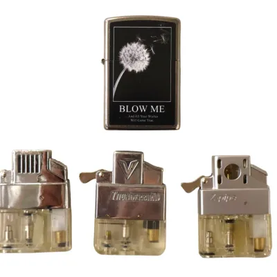 Sale Photo Thumbnail #195: Novelty Zippo-style flip lighter with a dandelion motif and caption, accompanied by three refillable lighter inserts including Thunderbird and Z-pipe models.