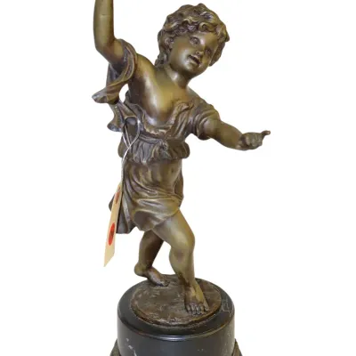 Sale Photo Thumbnail #100: 20th C Bronze figural sculpture of a cherub or child in classical attire, mounted on a round black marble base.