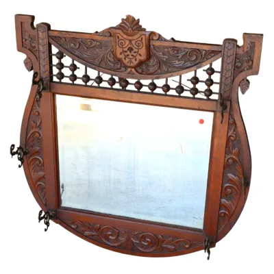 Sale Photo Thumbnail #254: Antique carved wooden wall mirror with coat hooks, featuring ornate acanthus scrollwork and a decorative spindle crest.
