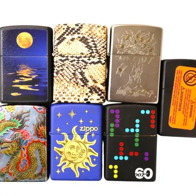 Sale Photo Thumbnail #159: Collection of seven decorated Zippo flip-top lighters featuring various designs, including celestial motifs, a full moon reflection, snakeskin, and an Asian dragon graphic.