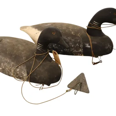 Sale Photo Thumbnail #86: Pair of vintage carved wood duck decoys with painted details, glass eyes, and attached rigging lines with a triangular lead weight.