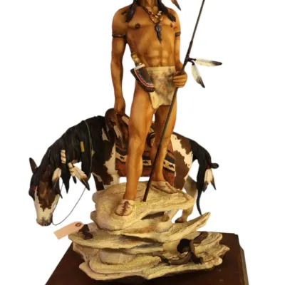 Sale Photo Thumbnail #60: RARE Bronn bisque porcelain detailed Native American warrior figurine with a horse, mounted on a tiered rock outcrop atop a wooden display base with a nameplate.