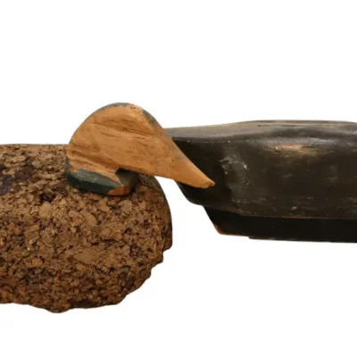 Sale Photo Thumbnail #95: Pair of vintage duck decoys, including a dark-painted carved wooden decoy alongside a textured cork body decoy with a wooden head.
