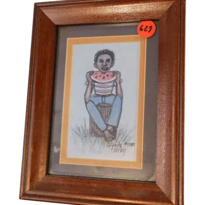 Sale Photo Thumbnail #136: Framed artwork by Glynda Turley, dated 1985, depicting a person eating a slice of watermelon in a dark wood frame.