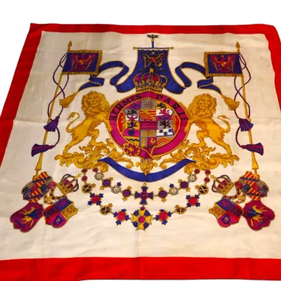 Sale Photo Thumbnail #79: Vintage silk scarf featuring a heraldic crest design with lions, crowns, and banners framed by a bold red border.