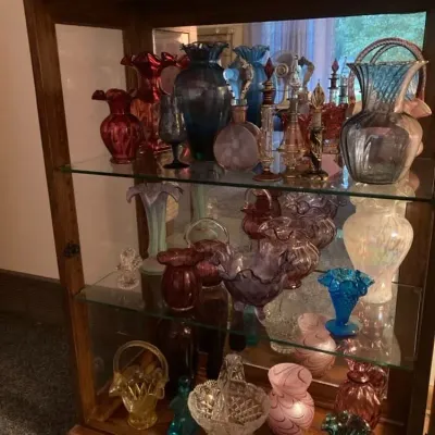 Sale Photo Thumbnail #6: Collection of vintage art glass, perfume bottles, and decorative vases displayed in a mirrored wooden display cabinet.