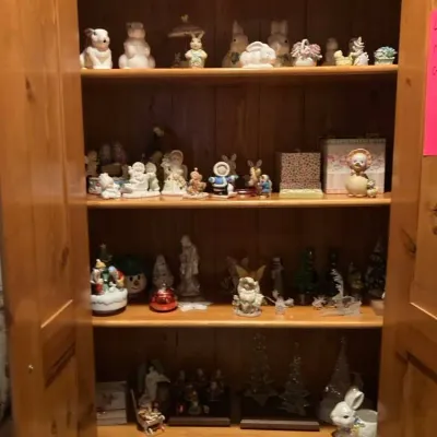 Sale Photo Thumbnail #11: Large wooden armoire with open double doors, filled with various collectible porcelain figurines including Easter bunnies, angels, and seasonal decor.