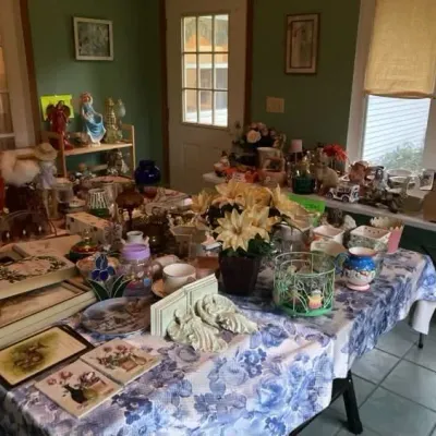 Sale Photo Thumbnail #8: Tables loaded with vintage home decor, including ceramic figurines, floral tableware, decorative boxes, artificial flower arrangements, and glassware.