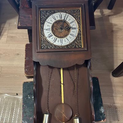 Sale Photo Thumbnail #25: Traditional dark wood pendulum wall clock featuring ornate scrollwork details, Roman numerals, and brass weights.