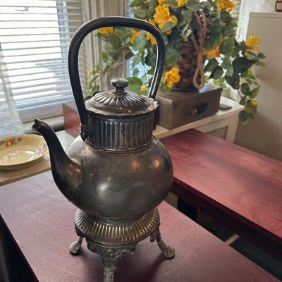 Sale Photo Thumbnail #7: Antique tarnished silver-plated tea kettle on an ornate footed warming stand, featuring fluted details and an arched overhead handle.