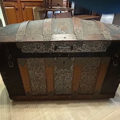 Sale Photo Thumbnail #112: Antique dome-top steamer trunk featuring embossed tin panels with leaf motifs, wooden slats, and metal hardware, late 19th to early 20th century.