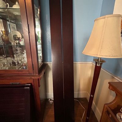 Sale Photo Thumbnail #73: Pair of dark espresso-stained wooden bed rails standing upright next to a modern floor lamp.