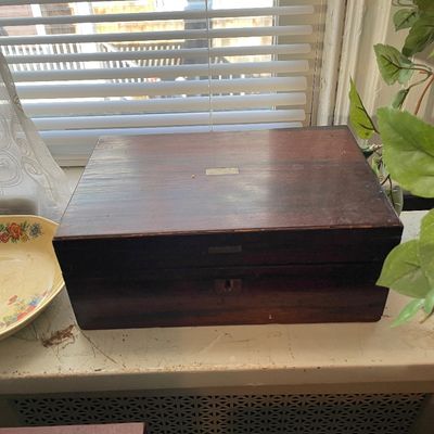 Sale Photo Thumbnail #38: Antique wooden writing slope or lap desk featuring a brass keyhole and an inlaid brass plaque on the lid.