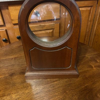 Sale Photo Thumbnail #18: Vintage arched wooden clock case with a circular glass face frame, sitting empty without its movement.