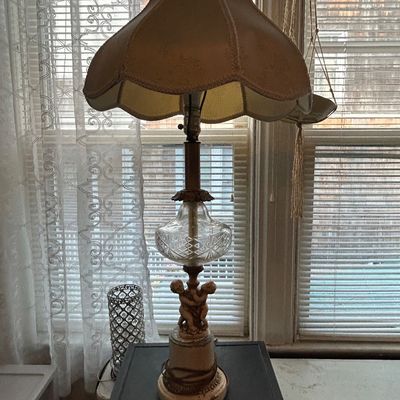 Sale Photo Thumbnail #90: Vintage table lamp featuring a cherub or putti base, cut glass accent globe, and a scalloped cloth lampshade.