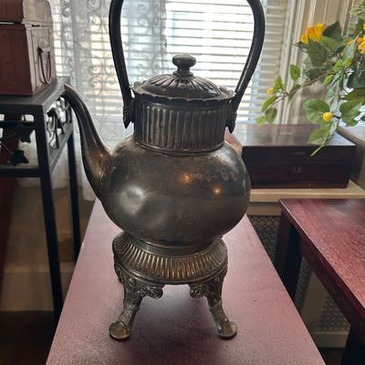 Sale Photo Thumbnail #6: Antique silver-plated tea kettle on a matching stand, featuring an ornate fluted design, raised feet, and a high fixed overhead handle.