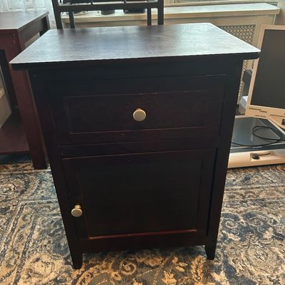 Sale Photo Thumbnail #88: Dark espresso wooden nightstand featuring a single top drawer, lower cabinet door, and simple round metal knobs.
