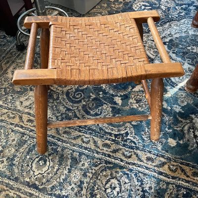 Sale Photo Thumbnail #39: Vintage wooden footstool featuring a woven split-reed top and turned legs with side handles, showing age-appropriate wear and finish distressing.