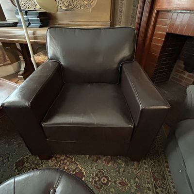 Sale Photo Thumbnail #116: Dark brown faux leather armchair with wide track arms, showing minor light wear on the seat.