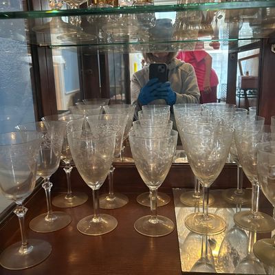 Sale Photo Thumbnail #58: Collection of vintage etched crystal stemware displayed inside a wooden curio cabinet, with gold-rimmed glassware on the shelf above.