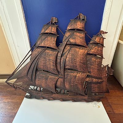 Sale Photo Thumbnail #85: Vintage copper-tone plastic or metal 3D sailing ship wall decor, featuring detailed sails and a three-masted design.