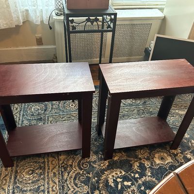 Sale Photo Thumbnail #86: Pair of matching dark reddish-brown wooden end tables with lower storage shelves, resting on a patterned area rug.