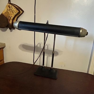 Sale Photo Thumbnail #122: Vintage black and metal adjustable piano or banker's desk lamp, featuring a double-stem support and cylindrical shade.