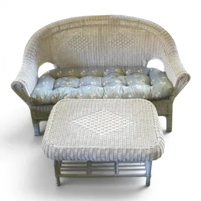 White wicker patio sofa with blue floral cushion coffee table