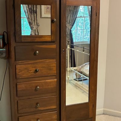 Sale Photo Thumbnail #207: Vintage solid wood chifferobe featuring a full-length mirrored wardrobe door, a smaller mirrored cabinet, and five stacked drawers with ornate metal knobs.