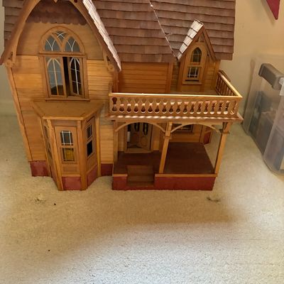 Sale Photo Thumbnail #196: Handcrafted wooden Victorian-style dollhouse featuring a shingled roof, front porch, and detailed window trim.
