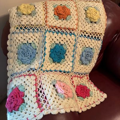 Sale Photo Thumbnail #210: Handmade crochet granny square afghan featuring colorful 3D floral motifs on a cream-colored base.