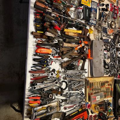 Sale Photo Thumbnail #16: Large assortment of hand tools arranged on a folding table, including screwdrivers, wrenches, pliers, hammers, and pipe wrenches.