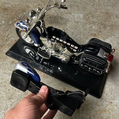 Sale Photo Thumbnail #58: Novelty Harley-Davidson cruiser motorcycle landline telephone with flame details and studded saddlebags on a display stand, with the seat handset removed.