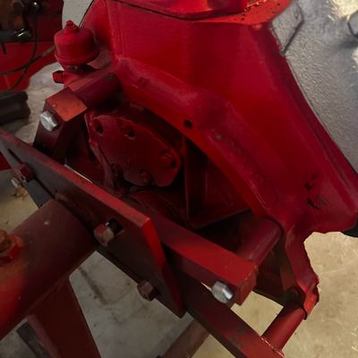 Sale Photo Thumbnail #52: Vintage painted red automotive engine block mounted on a heavy-duty engine stand.