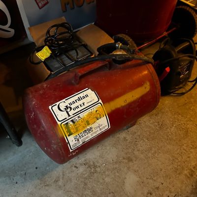 Sale Photo Thumbnail #9: Vintage Guardian Power portable red air tank showing light surface wear and original labels, sitting on a concrete floor alongside electrical cords and shop equipment.