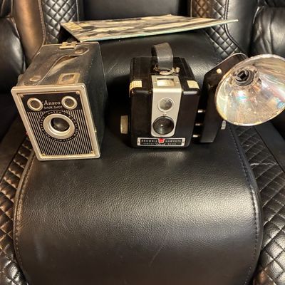 Sale Photo Thumbnail #177: Pair of vintage mid-century box cameras, featuring an Ansco Shur Shot and a Kodak Brownie Hawkeye Flash Model with attached flash reflector.