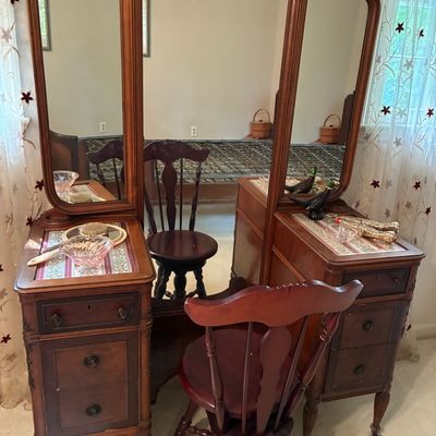 Sale Photo Thumbnail #219: Vintage dark wood vanity with a three-way tri-fold mirror and matching swivel chair, featuring glass vanity accessories on the tabletop.
