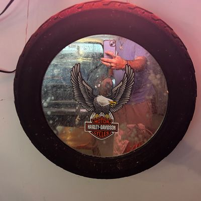 Sale Photo Thumbnail #171: Novelty Harley-Davidson wall mirror framed with a rubber motorcycle tire, featuring a bald eagle decal and iconic logo graphics.