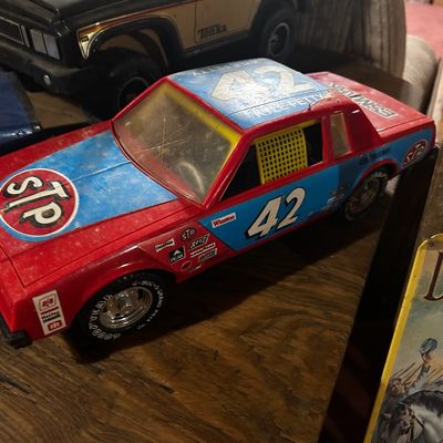 Sale Photo Thumbnail #128: Vintage plastic Kyle Petty #42 STP stock car toy showing light surface dust and play wear, alongside other vintage toy vehicles.