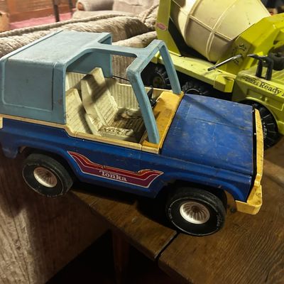Sale Photo Thumbnail #131: Vintage blue and light blue Tonka Bronco truck with a bright yellow Tonka cement mixer truck sitting behind it, both showing minor play wear.