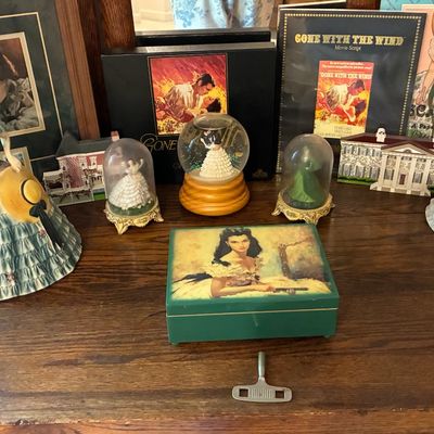Sale Photo Thumbnail #206: Collection of Gone with the Wind memorabilia, including porcelain Scarlett O'Hara figurines, music box, snow globes, framed artwork, and script.