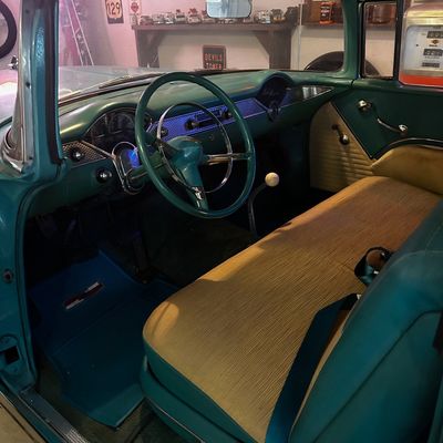Sale Photo Thumbnail #68: Vintage 1955 Chevrolet Bel Air interior featuring teal painted trim, patterned bench seats, and original-style dashboard and steering wheel.