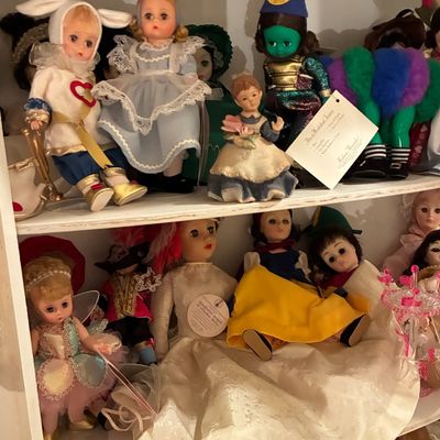 Sale Photo Thumbnail #218: Collection of vintage Madame Alexander and character storybook dolls displayed on wooden shelves, including Alice in Wonderland and Snow White.